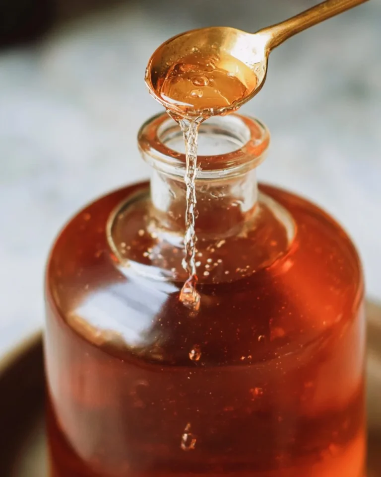 Homemade honey simple syrup in a glass jar with honeycomb