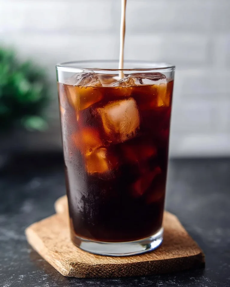 A glass of cold brew coffee served with ice and a straw.