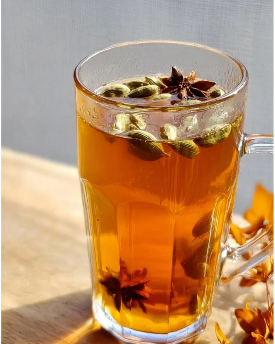 Cup of cardamom tea with spices and herbs on a wooden table