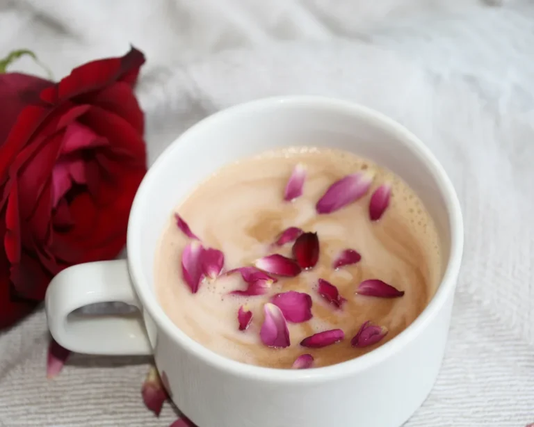 Delicious rose vanilla latte topped with rose petals and whipped cream in a latte glass.