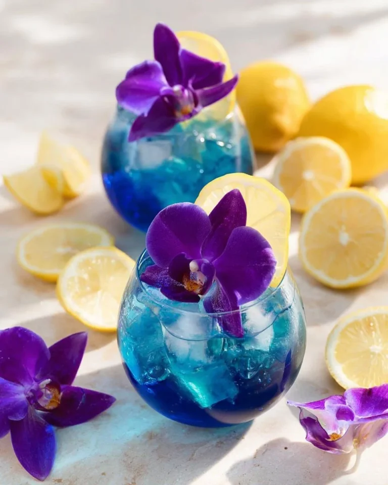 Blue Lagoon mocktail in a glass with a slice of lime and a cherry on top